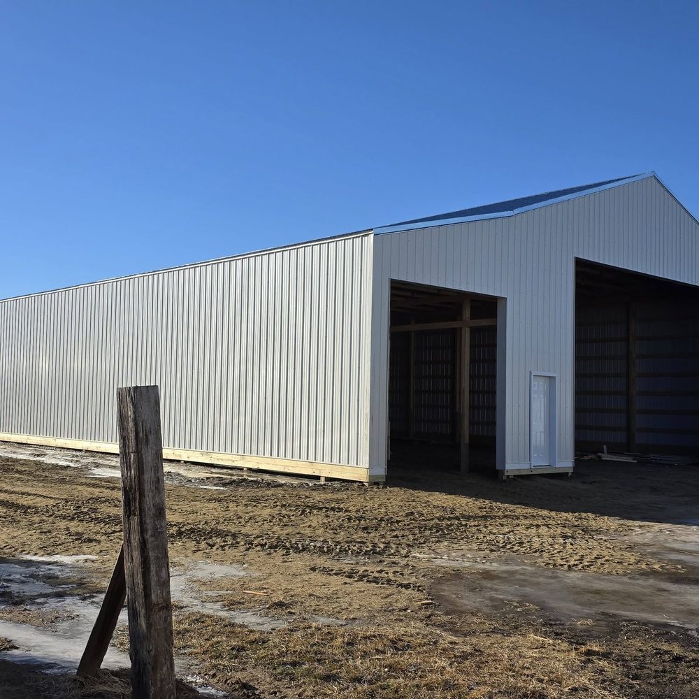 A white machine shed with both bay doors open on a clear day