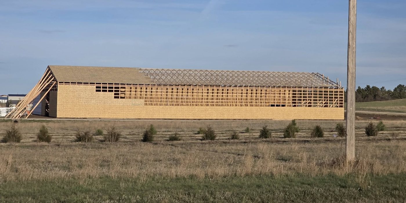 A long building framed and sheathed, photographed at golden hour